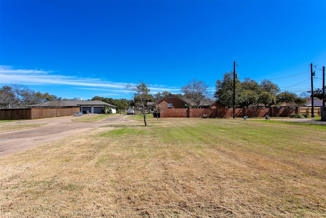 view of yard featuring fence, driveway, and a garage
