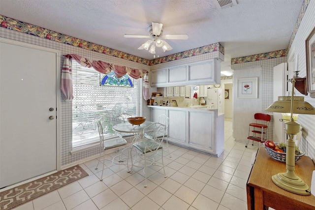 kitchen featuring ceiling fan, white refrigerator with ice dispenser, wallpapered walls, and light tile patterned floors