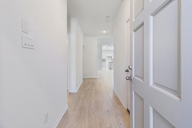 corridor with baseboards and light wood-type flooring