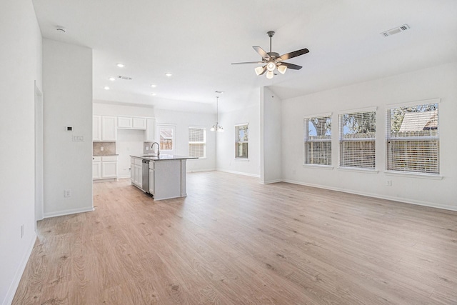 unfurnished living room with a ceiling fan, a sink, light wood finished floors, baseboards, and visible vents