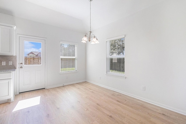 unfurnished dining area featuring light wood finished floors, baseboards, and a chandelier