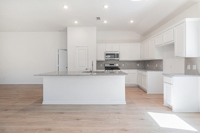kitchen with visible vents, a sink, appliances with stainless steel finishes, and light stone counters