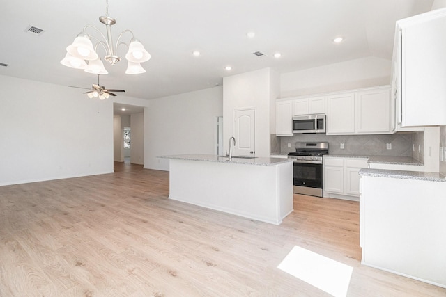kitchen with stainless steel appliances, light wood-type flooring, white cabinetry, decorative backsplash, and light stone counters