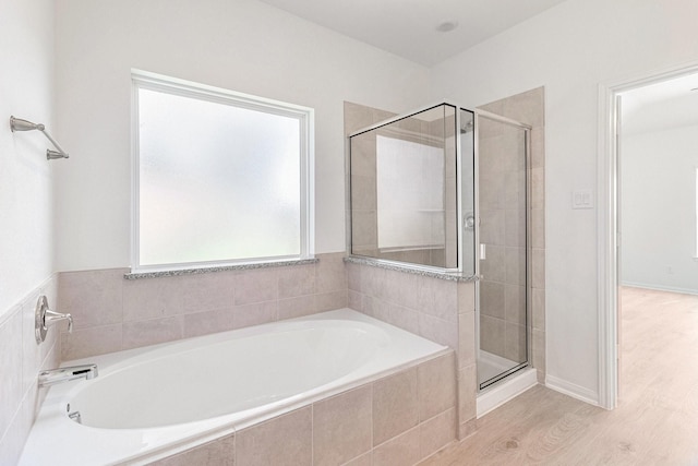 bathroom with a bath, wood finished floors, and a shower stall