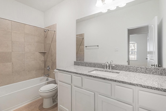 bathroom with wood finished floors, tub / shower combination, vanity, and toilet