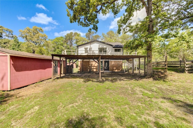 back of property with a lawn, a wooden deck, fence, and an outbuilding