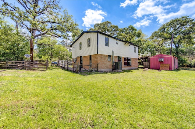view of home's exterior featuring central AC unit, an outdoor structure, fence, a yard, and brick siding