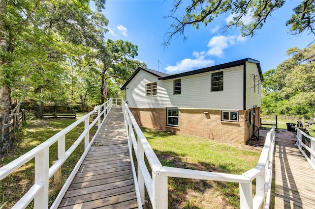 back of house featuring fence, a lawn, and brick siding