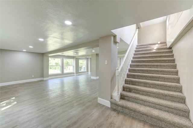 stairs featuring wood finished floors, baseboards, recessed lighting, and a textured ceiling