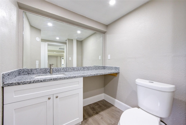 bathroom with recessed lighting, wood finished floors, toilet, vanity, and baseboards