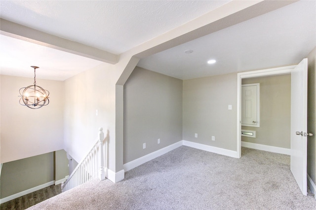 spare room featuring carpet floors, an inviting chandelier, and baseboards