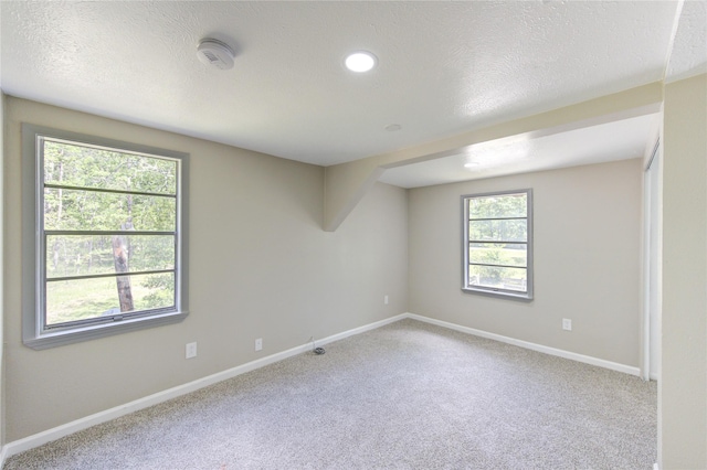 empty room featuring carpet, a textured ceiling, and baseboards
