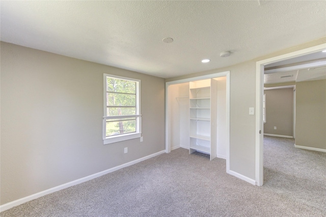 unfurnished bedroom featuring a closet, carpet floors, a textured ceiling, and baseboards