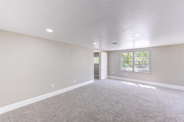 spare room featuring a textured ceiling, baseboards, visible vents, recessed lighting, and light colored carpet