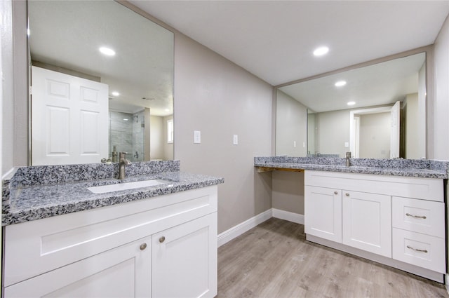 full bathroom with baseboards, wood finished floors, a sink, and a stall shower