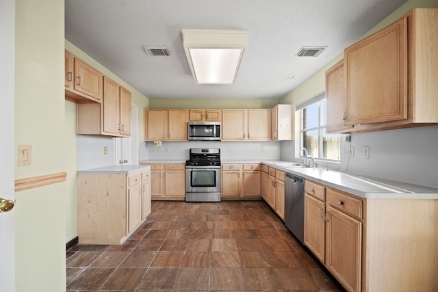 kitchen with appliances with stainless steel finishes, light brown cabinetry, visible vents, and light countertops