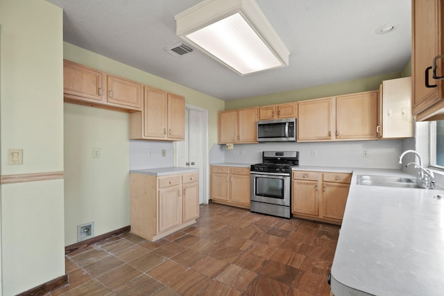kitchen with stainless steel appliances, light brown cabinetry, a sink, visible vents, and light countertops