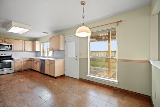 kitchen featuring light brown cabinets, hanging light fixtures, stainless steel appliances, light countertops, and visible vents