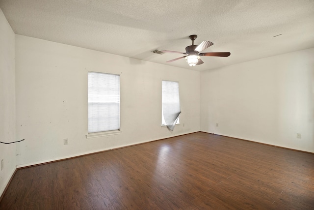 spare room featuring dark wood-style floors, visible vents, baseboards, a textured ceiling, and ceiling fan