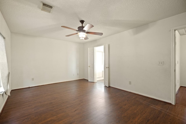 empty room featuring dark wood finished floors, visible vents, a ceiling fan, and a textured ceiling