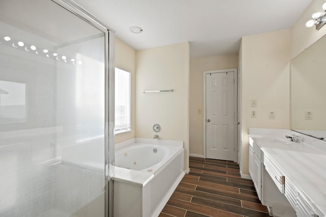full bath with wood tiled floor, vanity, a shower with shower door, a jetted tub, and baseboards