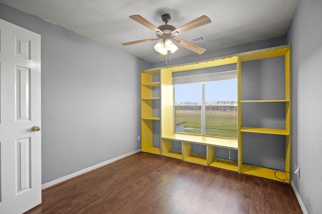 unfurnished room featuring wood finished floors, visible vents, a ceiling fan, and baseboards