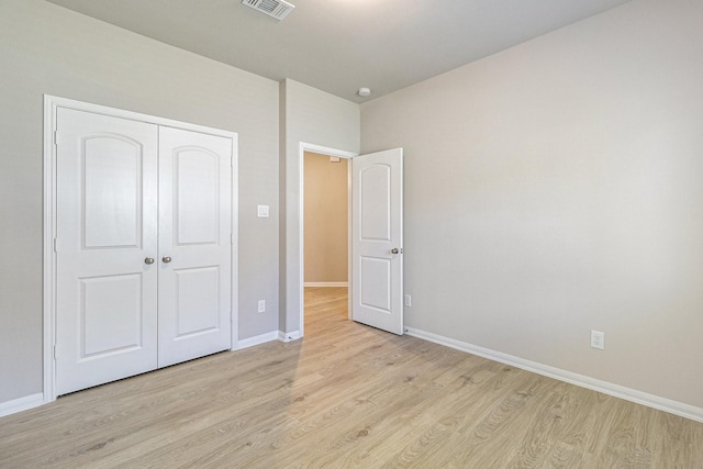 unfurnished bedroom featuring a closet, visible vents, light wood finished floors, and baseboards