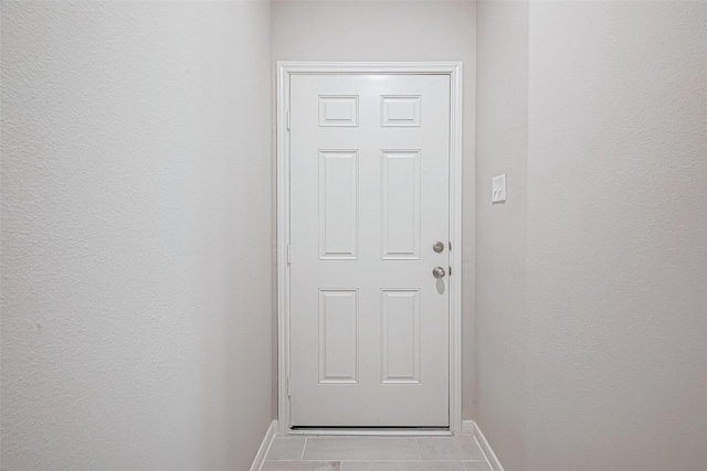 entryway with a textured wall, baseboards, and light tile patterned flooring