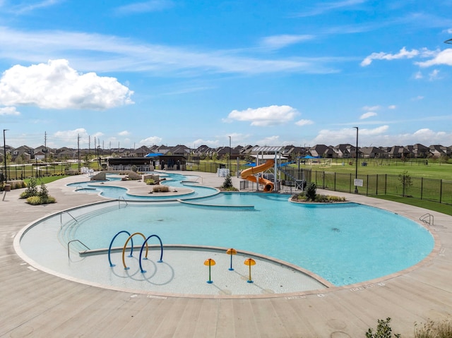 pool featuring a residential view, a water slide, and fence
