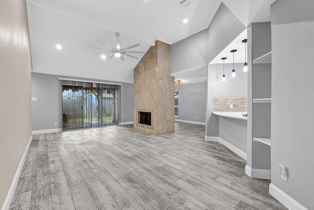 unfurnished living room featuring a fireplace, wood finished floors, baseboards, and ceiling fan