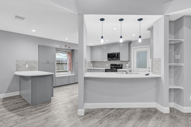 kitchen with electric stove, gray cabinets, a sink, stainless steel microwave, and a peninsula
