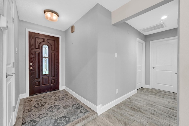 foyer entrance featuring light wood-type flooring, baseboards, and visible vents