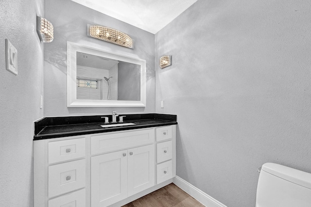 bathroom with baseboards, toilet, vanity, and wood finished floors