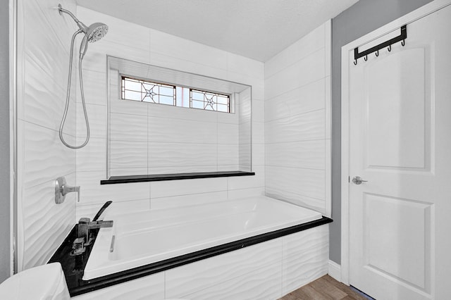 bathroom with walk in shower, a textured ceiling, a bathing tub, and wood finished floors