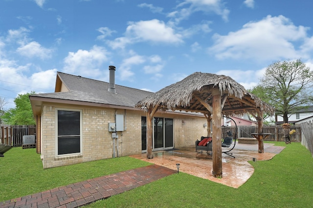 back of property featuring a fenced backyard, a yard, roof with shingles, a patio area, and brick siding
