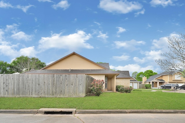 view of front of house featuring fence, roof with shingles, a front yard, and a garage