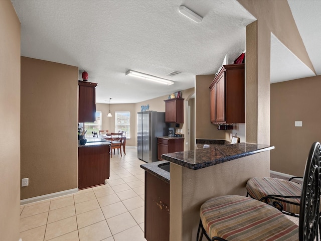 20819 Mount Bauer Dr, Hockley, TX 77447 - kitchen with dark countertops, visible vents, freestanding refrigerator, baseboards, and a peninsula