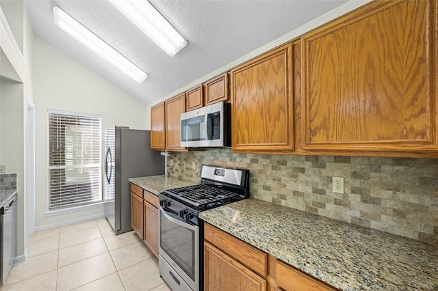 17402 Eastwood Cir, Houston, TX 77095 - kitchen with appliances with stainless steel finishes, lofted ceiling, brown cabinets, backsplash, and light tile patterned floors