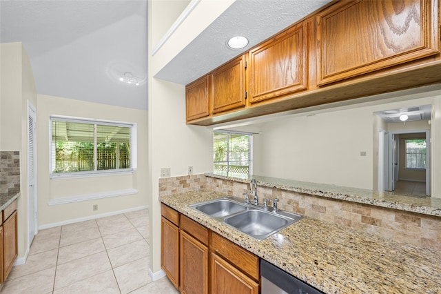 17402 Eastwood Cir, Houston, TX 77095 - kitchen featuring a sink, decorative backsplash, light tile patterned flooring, brown cabinets, and plenty of natural light