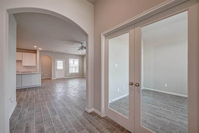 interior space with french doors, a ceiling fan, wood tiled floor, and arched walkways
