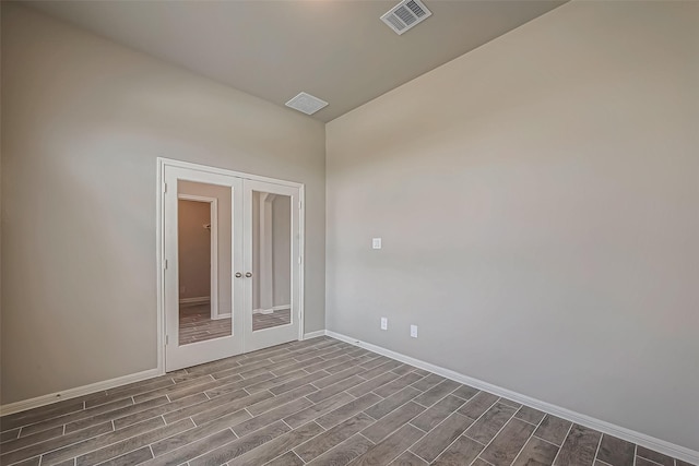 empty room with baseboards, visible vents, french doors, and dark wood-style floors