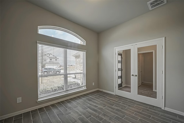 unfurnished room with wood tiled floor, visible vents, baseboards, and french doors