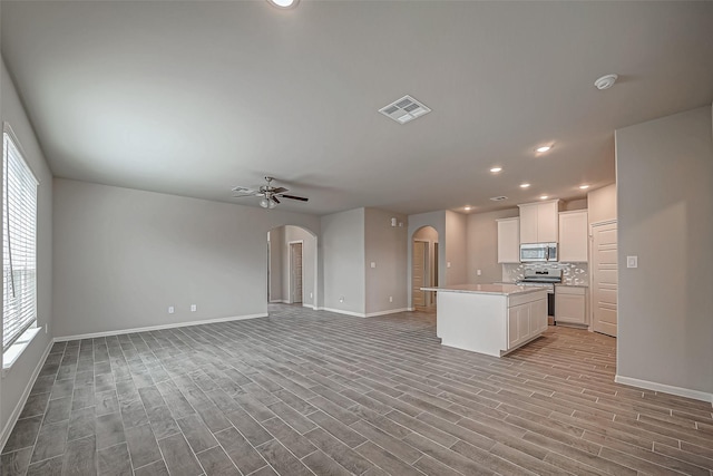 kitchen featuring stainless steel appliances, visible vents, arched walkways, baseboards, and open floor plan