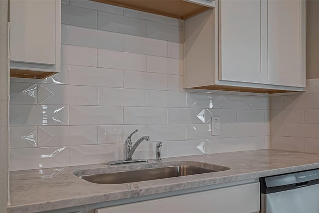 kitchen featuring backsplash, light stone countertops, stainless steel dishwasher, and a sink