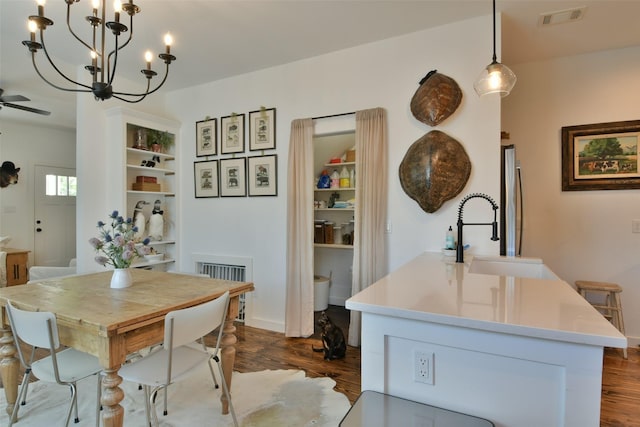 dining area featuring dark wood finished floors, visible vents, and ceiling fan with notable chandelier