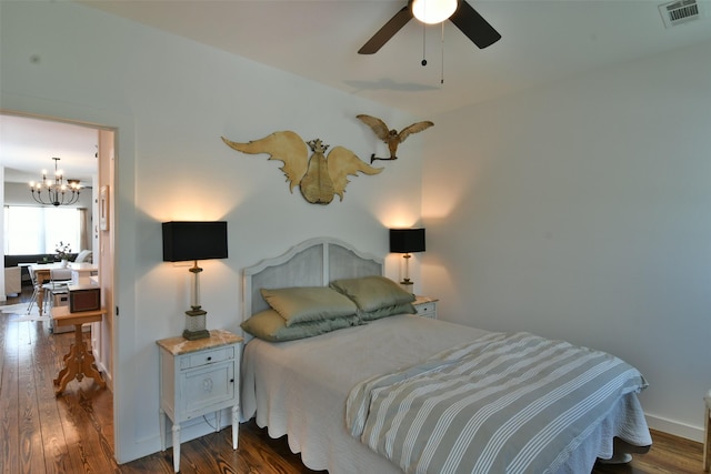 bedroom with ceiling fan with notable chandelier, visible vents, and dark wood finished floors