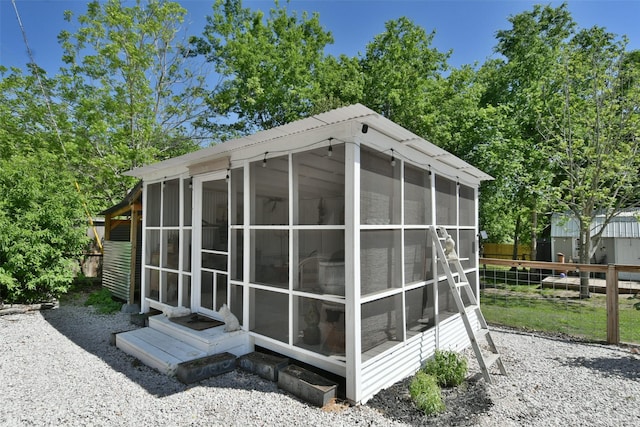 view of outbuilding featuring entry steps, a sunroom, and fence
