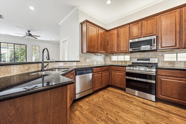 5308 Larkin St Unit B, Houston, TX 77007 - kitchen featuring stainless steel appliances, dark stone countertops, backsplash, a sink, and light wood-style floors