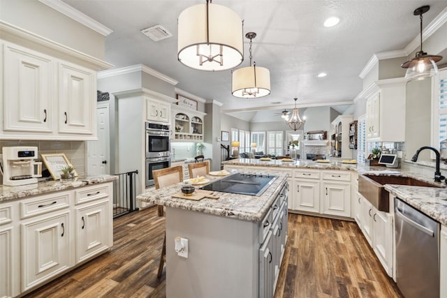 kitchen with stainless steel appliances, a sink, visible vents, a notable chandelier, and dark wood-type flooring