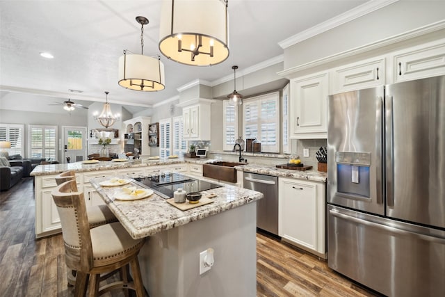 kitchen featuring stainless steel appliances, a peninsula, a sink, open floor plan, and ceiling fan with notable chandelier